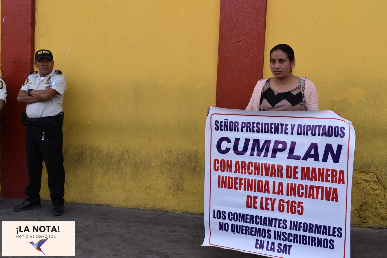 Una manifestante en Quiché pide que el Congreso archive la iniciativa 6165 que incorpora a comerciantes informales al sistema tributario. Foto de Julián Ventura